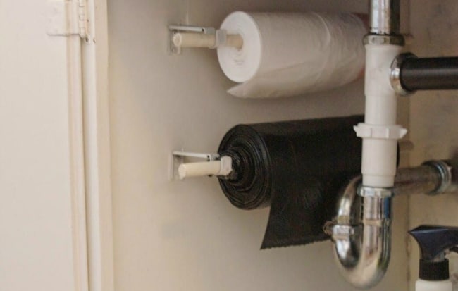 Для удобства многие домохозяйки устанавливают под мойкой простые держатели для туалетной бумаги, нанизывая на них рулон мусорных пакетов